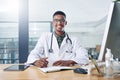 Seeing you healthy makes me happy. a handsome young doctor sitting alone in his office at the clinic and writing in his Royalty Free Stock Photo
