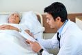 Seeking the problem. a handsome young doctor going through a senior patients chart. Royalty Free Stock Photo