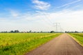 Seemingly endless country road in a rural area with power pylons Royalty Free Stock Photo