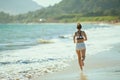 Young sports woman on ocean coast in evening jogging