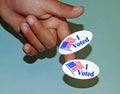 A child`s Hand holds two I voted stickers