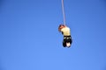 Bungee jumping. Seen from the ground beautiful young woman hanging on a cord high in the blue sky