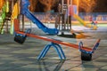Seesaw swing in preschool yard with soft rubber flooring at night