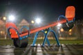 Seesaw swing in preschool yard with soft rubber flooring at night