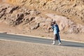 Lesotho, adult happy smiling african shepherd man waving hand gesture in national woolen blanket dress and hat walks on rural road