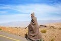 Lesotho, african young shepherd man in national wool blanket dress and balaclava cap goes along rural high mountain road, blue sky