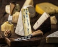 Segment of blue cheese or Cambozola cheese on wooden board. Different cheeses at the background