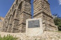 Low-angle shot of Unesco plaque commemorating World Heritage Site at the base of Roman aqueduct.