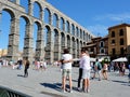 Segovia, Spain - August 7, 2021: Group of young people in virus protective masks hug eachother near aqueduct on a sunny day