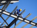 Construction workers install trusses and roofing sheets at construction sites.