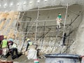 Construction workers are spraying liquid concrete onto the slope surface to form a retaining wall layer.