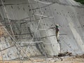 Construction workers are spraying liquid concrete onto the slope surface to form a retaining wall layer.