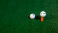 The close of view of the golf ball on the tee on the green carpet mat