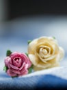 Select focus at pink artificial flowers. pink and yellow artificial flowers made of paper and placed on blue cloth stripes. Royalty Free Stock Photo