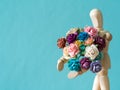 Select focus of wooden puppet. The wooden puppet holds flower and standing on the wood table. the background is blue