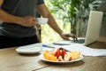 Selected focus fresh fruit with man holding cup of coffee working on laptop Royalty Free Stock Photo