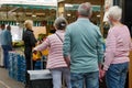 Elder couple and women with protective face mask queue with social distancing in outdoor market during COVID-19 epidemic.