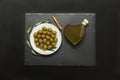 Selected olives in a white plate decorated with natural olive tree branches and olive oil heart bottle.