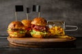 Selection of burgers and a serving of french fries served on wooden board