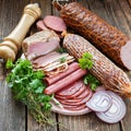 Selection of cold meats, including a variety of processed cold meat products, displayed on a wooden background. Royalty Free Stock Photo