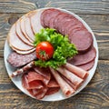 Selection of cold meats, including a variety of processed cold meat products, displayed on a wooden background. Royalty Free Stock Photo