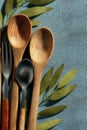 Natural wooden utensils arranged with green leaves on blue background Royalty Free Stock Photo