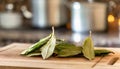A selection of fresh herbs: bay leaves, sitting on a chopping board against blurred kitchen background copy space