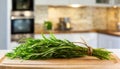 A selection of fresh herbs: tarragon, sitting on a chopping board against blurred kitchen background copy space