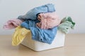 Selection of fresh unfolded laundry in white basket on wood table