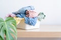 Selection of fresh unfolded laundry in white basket on wood table