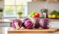 A selection of fresh vegetable: red cabbage, sitting on a chopping board against blurred kitchen background copy space Royalty Free Stock Photo