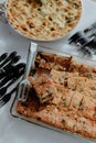 Selection of freshly-baked pies arranged on white paper with knives, ready to be enjoyed