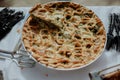 Selection of freshly-baked pies arranged on white paper with knives, ready to be enjoyed