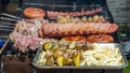 Selection of meat grilling over the coals on a portable barbecue with spicy sausages, beef kebabs and racks of ribs, outdoors