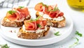 Assortment of prosciutto and ricotta cheese crostini with arugula and microgreens on a white plate Royalty Free Stock Photo