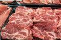 Selection of quality meat at a butcher shop, butchered pork in a refrigerated display case under glass, close up