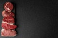 Selection of raw beef meat food steaks against black stone background.