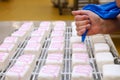 selection of sponge cakes with pink icing being added by hand Royalty Free Stock Photo