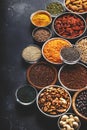 Selection of superfoods, legumes, cereals, nuts, seeds in bowls on black background. Superfood as chia, spirulina, beans, goji