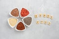 Selection of superfoods in white bowls on gray concrete background. Quinoa, chia, goji berry and flax seeds.