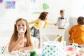 Selective focus of adorable kid sitting at table and eating cupcake during birthday party. Royalty Free Stock Photo