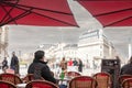 Selective blur on a client, a man, alone sitting at the terrace of a French brasserie, or cafe