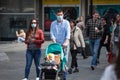 Selective blur on a European Family, a father and mother, and their baby, in a stroller, walking wearing face mask on covid