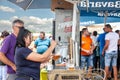 Selective blur on a female bartender, a woman barkeeper preparing draft beer, pouring it into glasses from a beer tap, outdoors