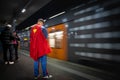 Selective blur on a man wearing a superman costume waiting for a train of the Cologne S-Bahn