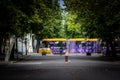 Selective blur on a Szged Tram passing in a park of Szeged in front of blurred people.