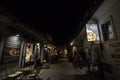 Selective blur on Trubarjeva cesta street at night with people passing by restaurants and fast foods.