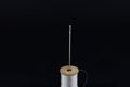 white thread reel and a sewing needle isolated on a black background in a studio shot. Spool (or reel), thread Royalty Free Stock Photo