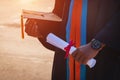 Selective and close-up focus of a university graduate holds a degree certificate and graduation cap celebrates in the graduation c Royalty Free Stock Photo