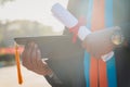 Selective and close-up focus of a university graduate holds a degree certificate and graduation cap celebrates in the graduation c Royalty Free Stock Photo